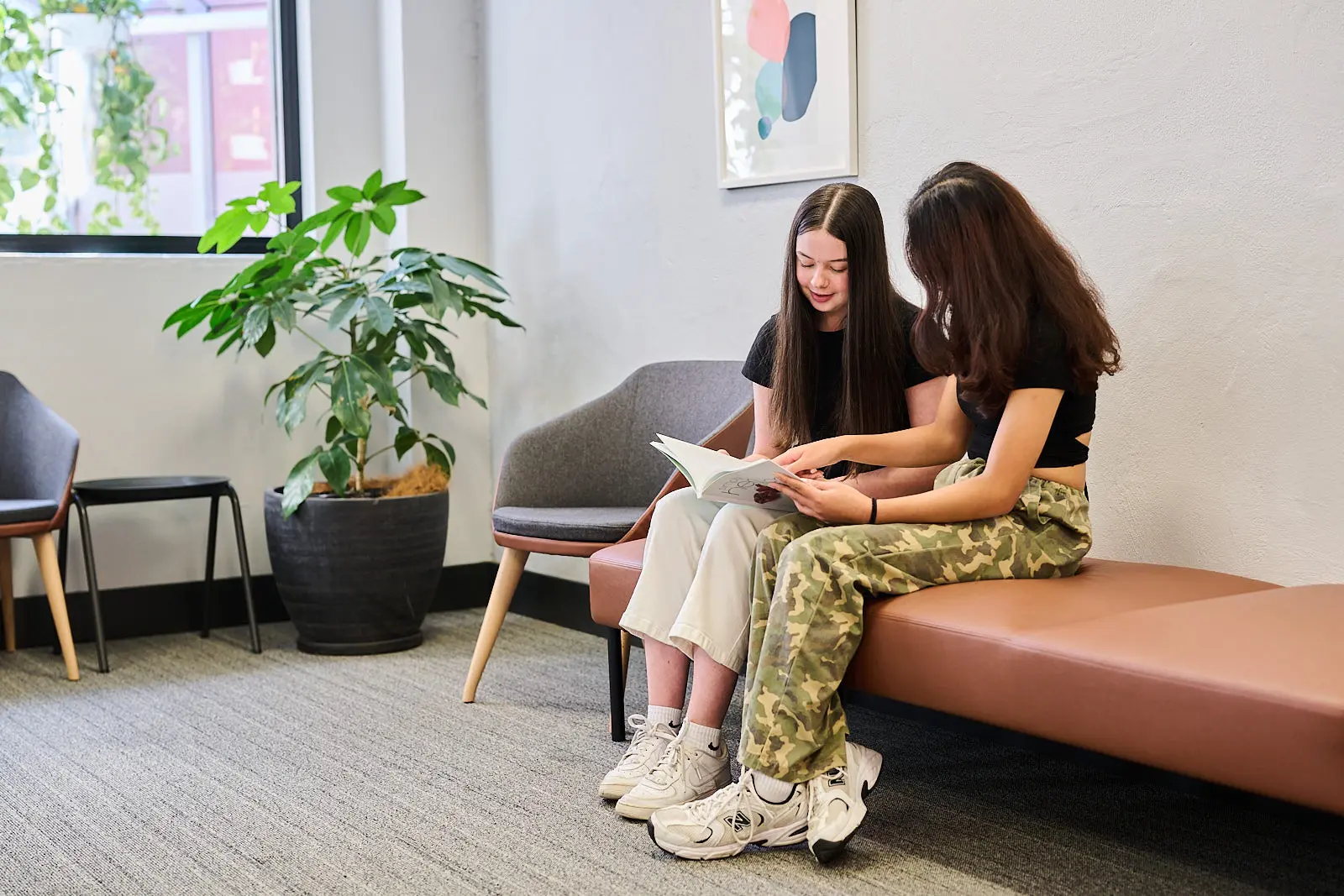 Two young women sitting together in a waiting area