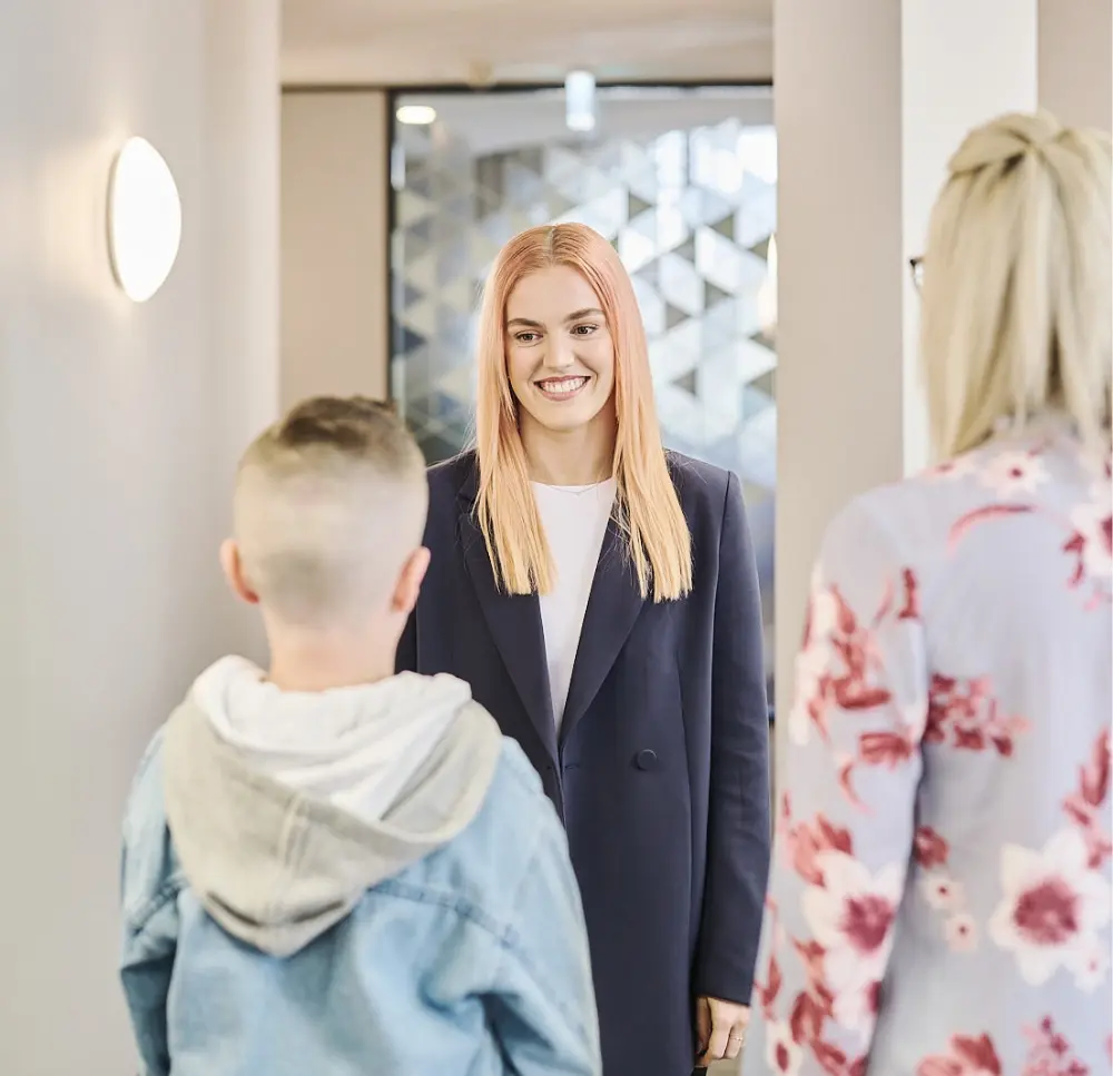 Psychologist greeting a child and parent in a hallway